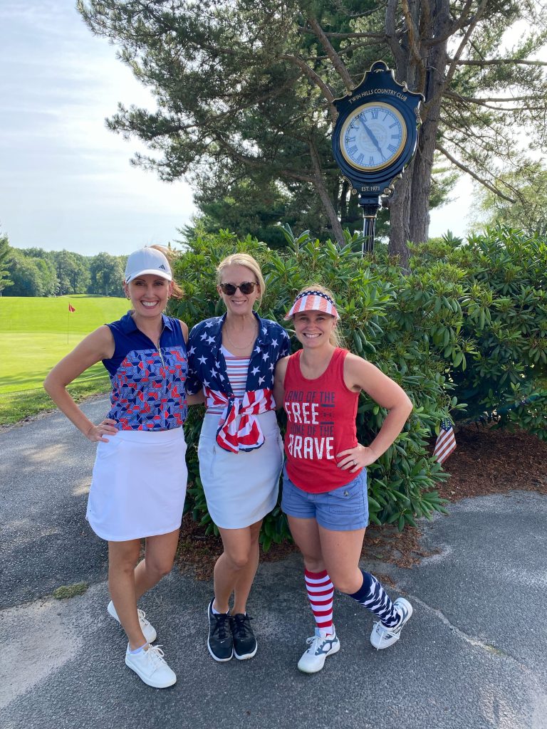 3 women in red and blue posing in front of the clock post at the course, celebrating the 4th of July.