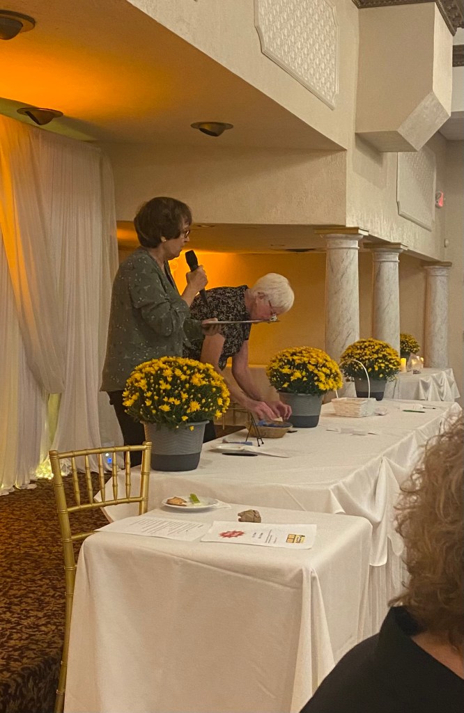 2 women are seen hosting a party at the clubhouse. One is holding a microphone.